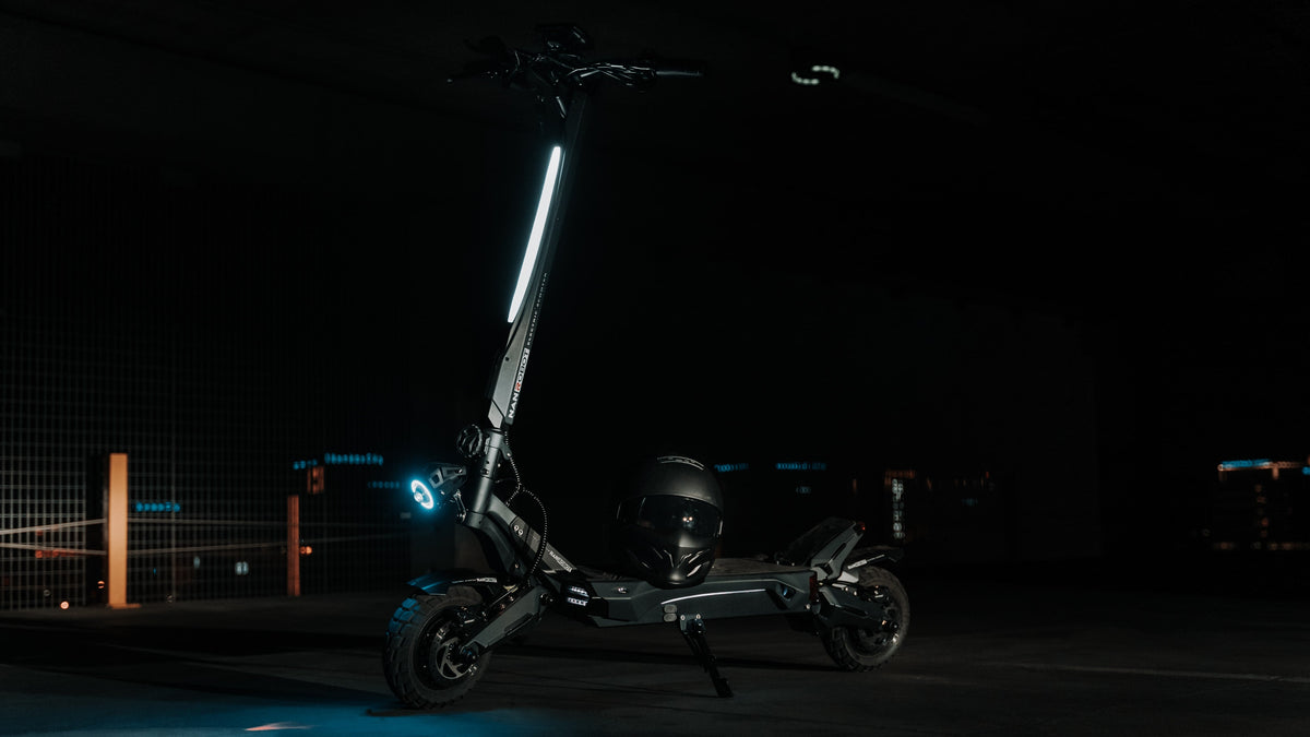 Schwarzer E-Scooter auf dem Seitenständer in einer dunklen Garage, ein Helm liegt auf dem Trittbrett
