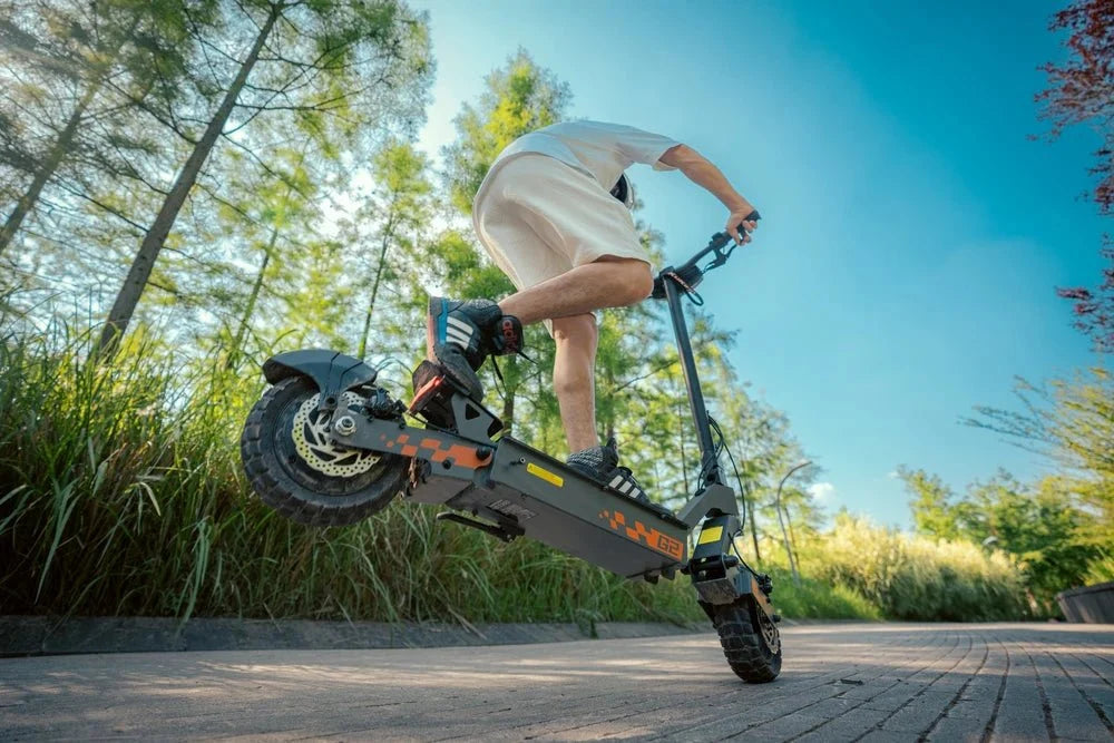 Fahrer springt mit einem schwarz-orangen KuKirin E-Scooter vom Bordstein – KuKirin G2 Pro vs G4 vs G2 Master