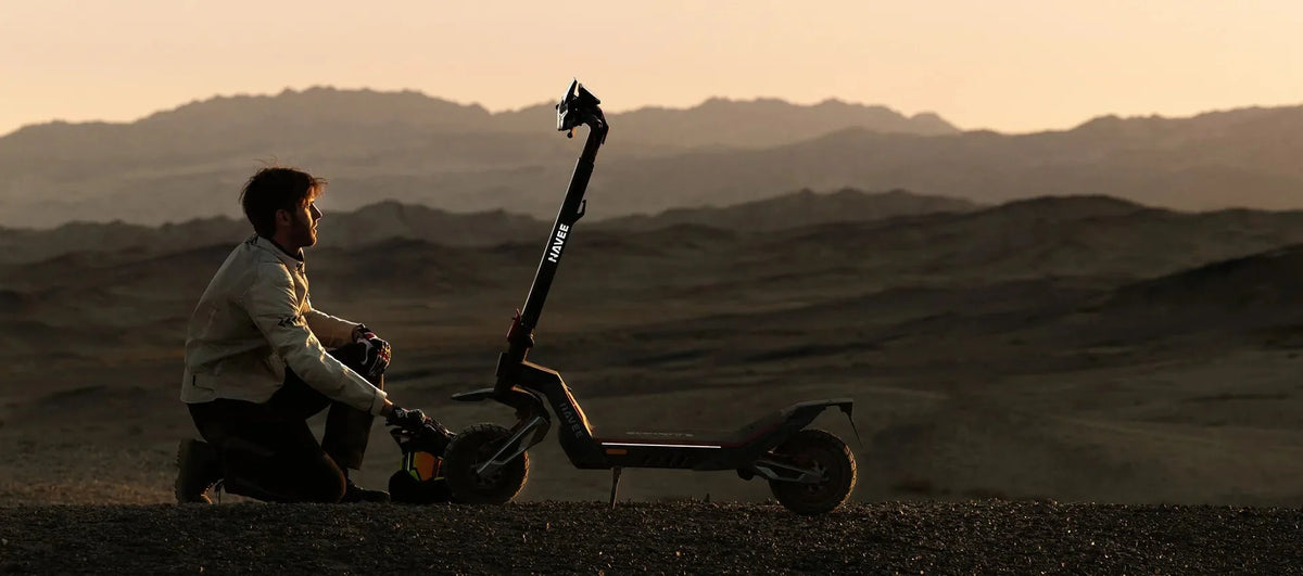 Mann kniet in der Dämmerung neben seinem E-Scooter und prüft ihn – so senkst du das Risiko für einen Akku-Brand