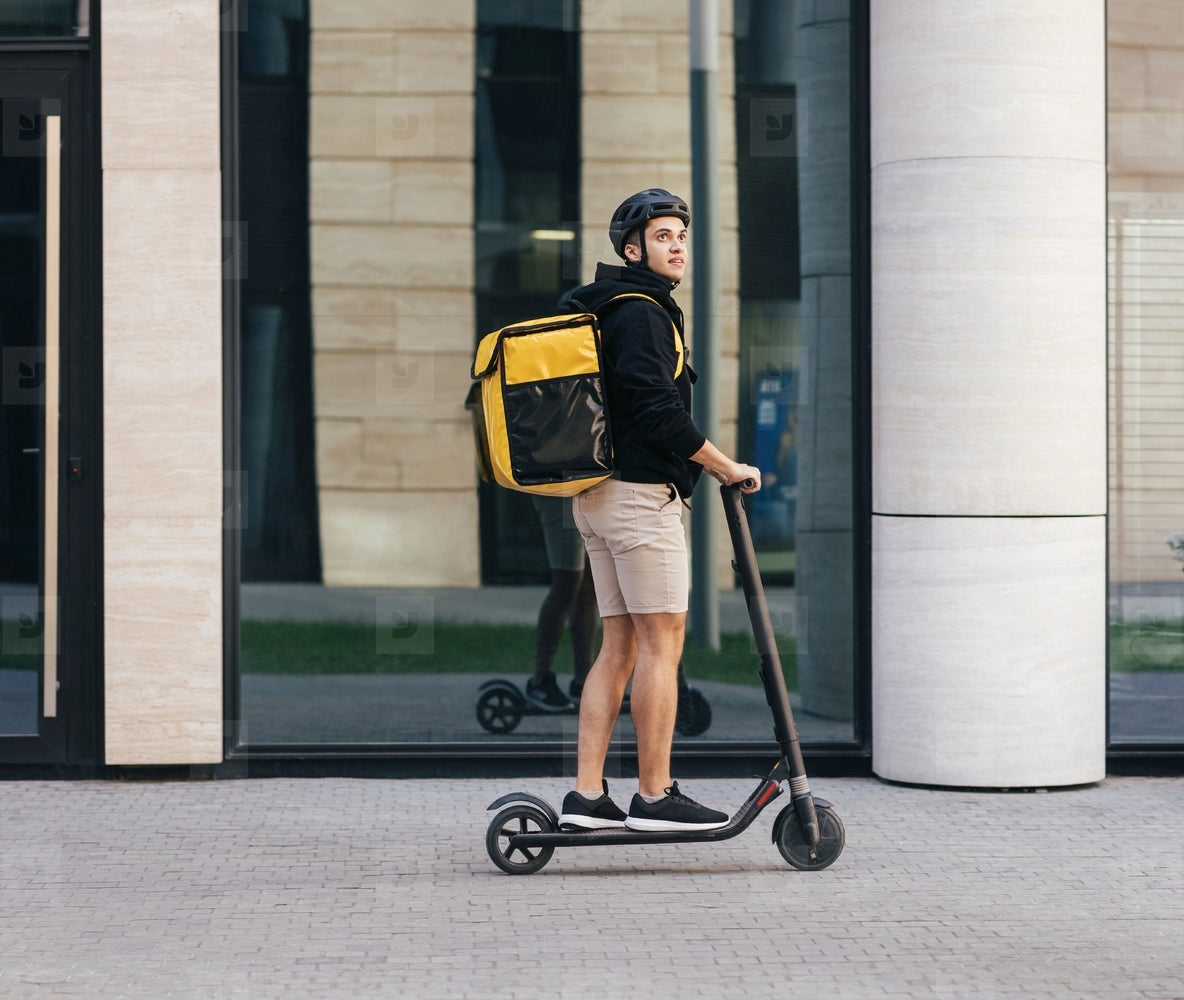 Kurier auf einem E-Scooter bei der Lieferung in der Stadt