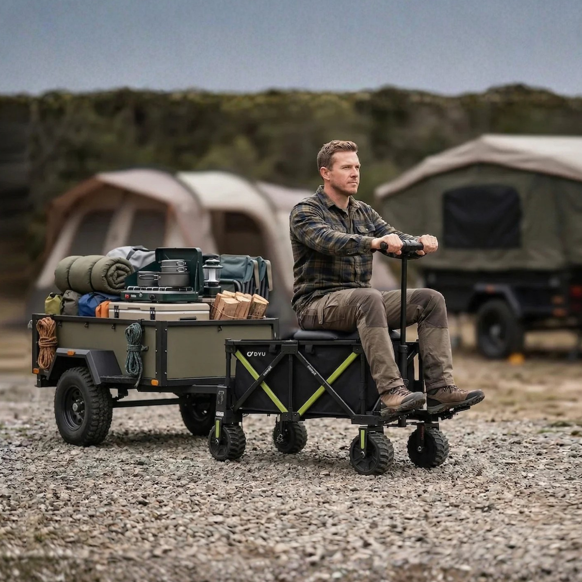 DYU CampX auf Schotter, ein Mann sitzt auf dem Wagen neben einem beladenen Anhänger und einem Zelt