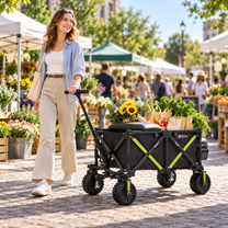 Eine Frau zieht den DYU CampX Wagen über einen Markt, mit Blumen und Einkaufstaschen auf dem Wagen