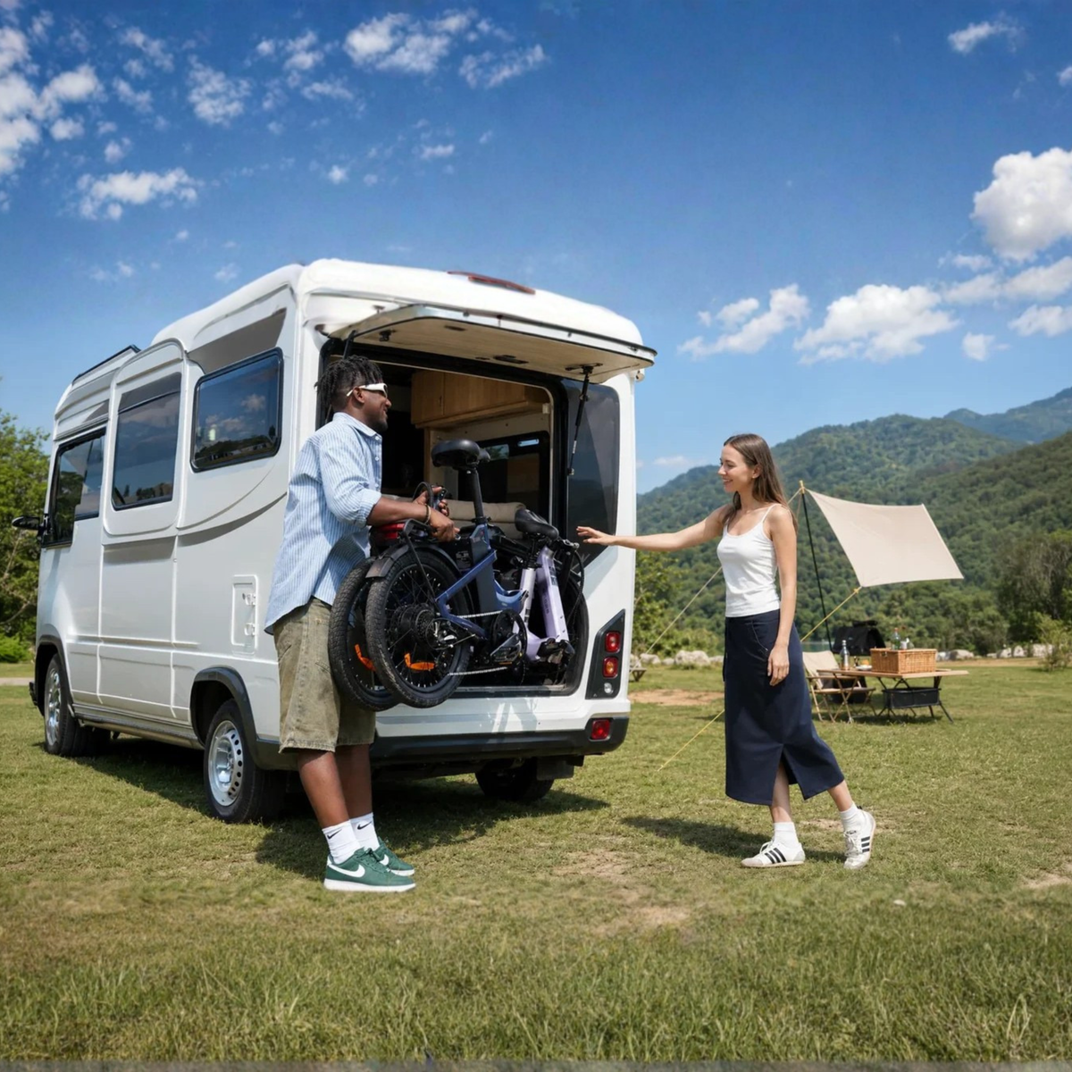 ENGWE O20 Boost – Mann hebt ein zusammengeklapptes Rad in ein weißes Wohnmobil, daneben steht eine Frau, im Hintergrund Wiese und Berge
