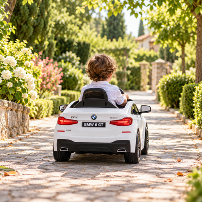 Kind fährt das BMW 6GT Elektroauto für Kinder auf einem Fußweg