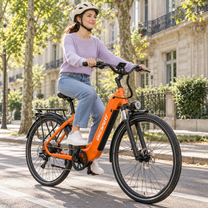 Frau mit Helm fährt ein orangefarbenes OneSport OT05 Max auf einer Straße mit Bäumen und Fassaden