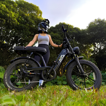 Frau auf dem TST R7 Fatbike-E-Bike in Schwarz auf einer Wiese