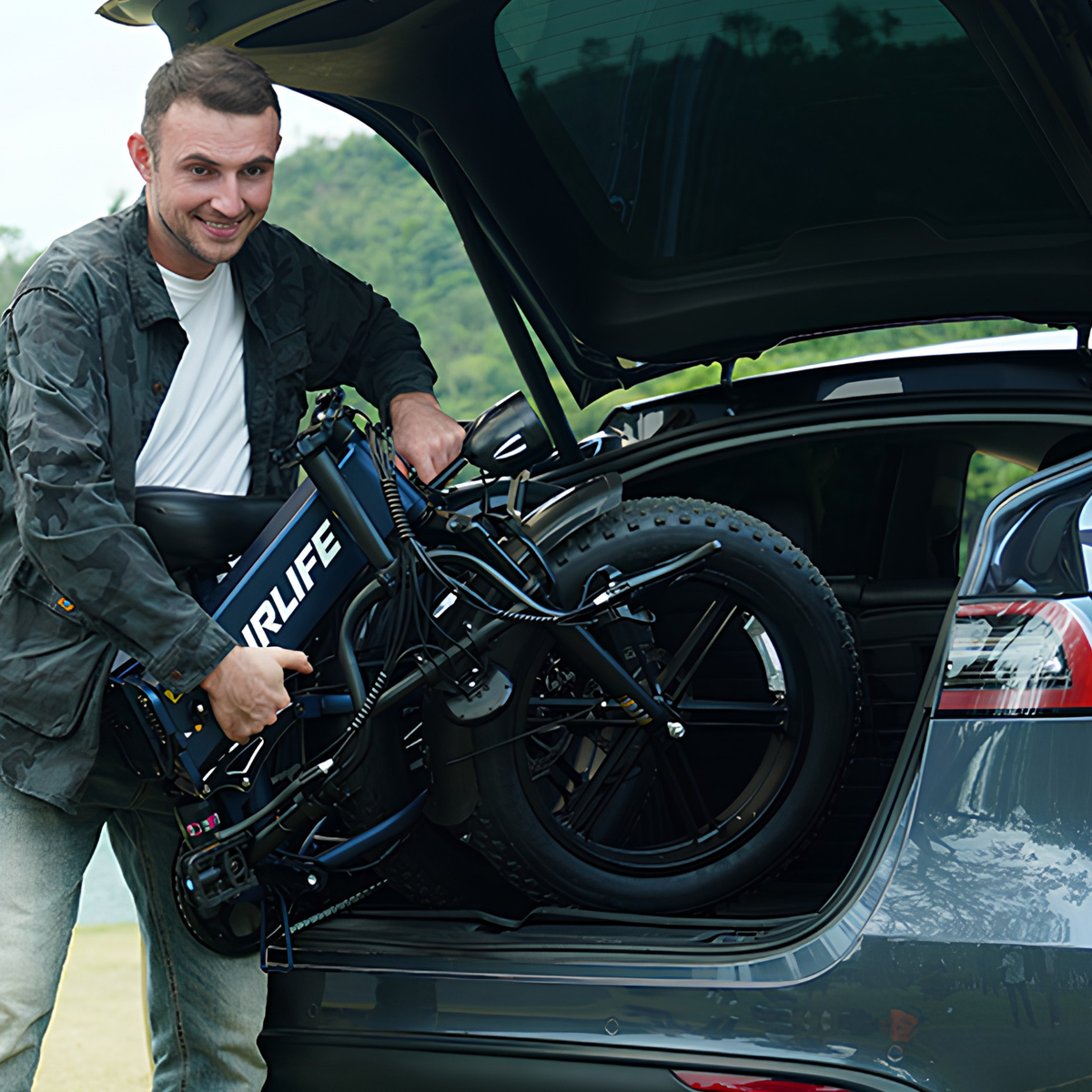 Lächelnder Mann lädt ein zusammengeklapptes URLIFE T5 in die Heckklappe eines Autos