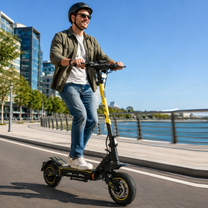 Mann mit Helm fährt den Wheely - H7 E-Scooter an einem Kai am Wasser entlang