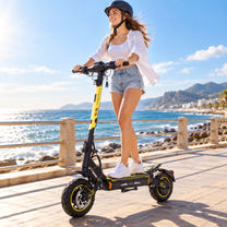 Frau mit Helm fährt den Wheely - H7 an einem sonnigen Tag auf einer Strandpromenade am Meer