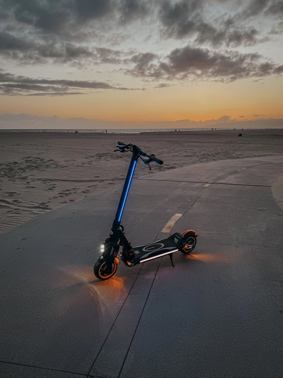 DUALTRON POPULAR E-Scooter schräg von vorne am Meer bei Sonnenuntergang