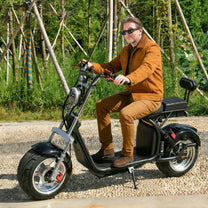 Mann sitzt auf dem eHoodax X10 City Road E-Scooter auf einem Schotterweg
