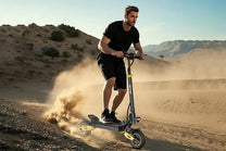 Mann auf dem iENYRID ES1 E-Scooter auf sandigem Untergrund