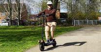 Person steht neben dem iScooter iX4 E-Scooter auf einer Wiese