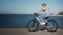 Person auf dem OneSport OT05 Pro E-Bike mit Helm am Meer in Hellblau