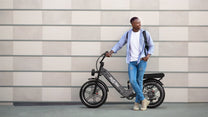 Mann steht neben dem OneSport OT08 Pro Fatbike-E-Bike in Grau auf einer Straße