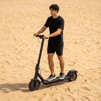 Mann steht neben dem SEEDREAM RED WING MINI E-Scooter auf sandigem Untergrund